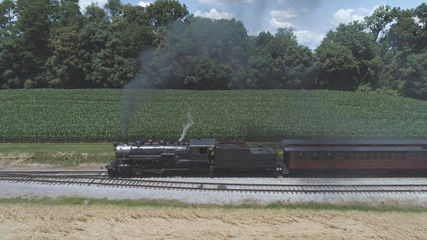 Aerial View of An Antique Restored Steam Locomotive Blowing Smoke and Steam Traveling Thru Farmlands and Countryside on a Sunny Summer Day