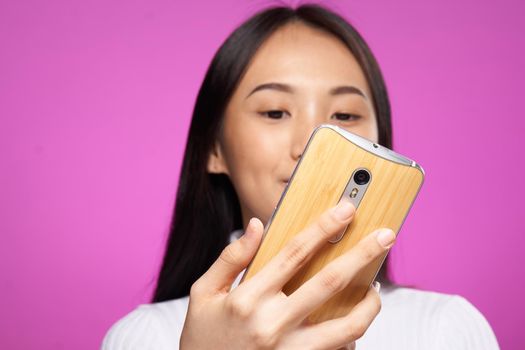 pretty brunette with a phone in her hands chatting internet online pink background. High quality photo