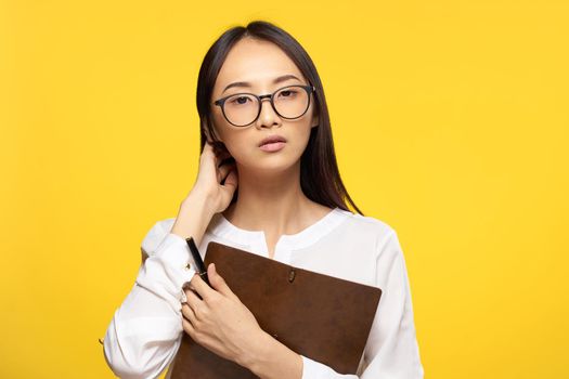 Business woman in glasses with notepad in hands executive secretary yellow background. High quality photo