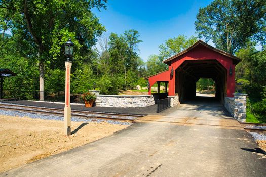 A Restored Covered Bridge Near a Rail Road Track on a Sunny Day