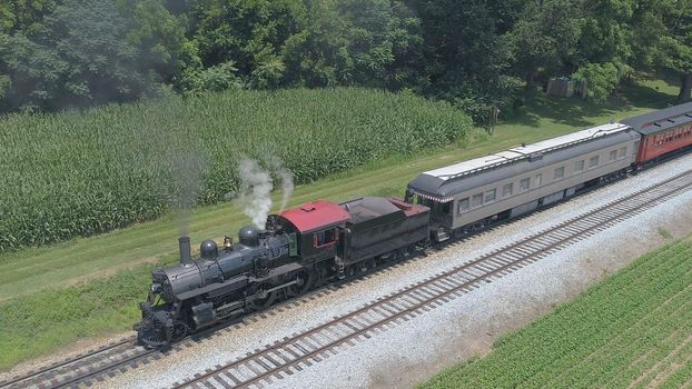 Aerial View of An Antique Restored Steam Locomotive Blowing Smoke and Steam Traveling Thru Farmlands and Countryside on a Sunny Summer Day