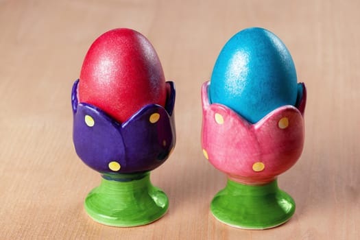 Colored easter eggs in egg cups on wooden table