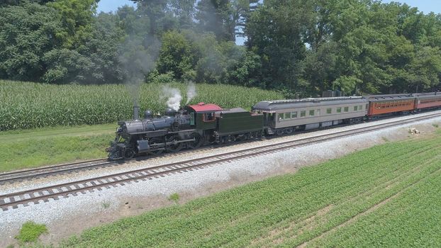 Aerial View of An Antique Restored Steam Locomotive Blowing Smoke and Steam Traveling Thru Farmlands and Countryside on a Sunny Summer Day