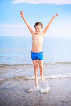 jumping boy with smile on the beach