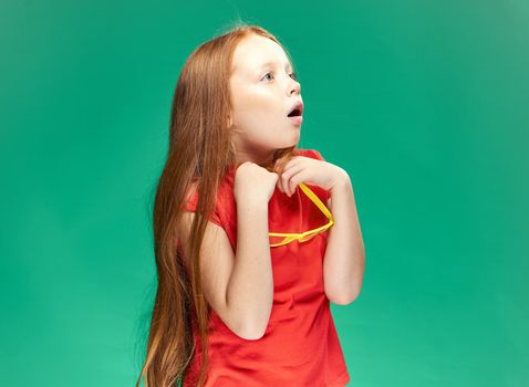 cute red-haired girl with glasses on her head red t-shirt Studio Green background. High quality photo