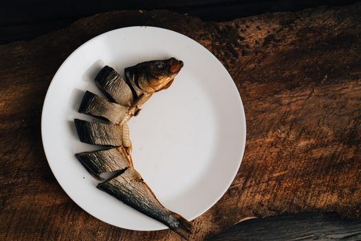 sliced dried fish on a white plate on a wooden table. High quality photo
