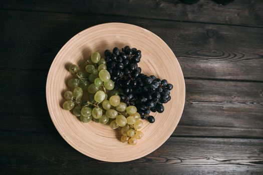 white and black grapes on a plate juiciness freshness vitamins. High quality photo