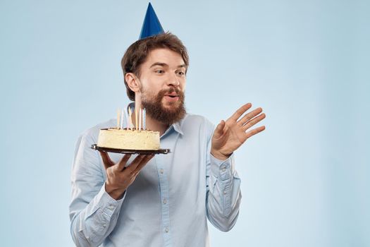 cake in a plate and birthday man with a cap on his head blue backgroun. High quality photo