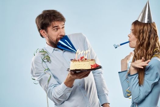 Emotional man with cake and pretty woman party disco blue background. High quality photo