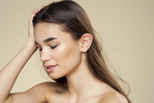 Pretty woman naked shoulders long hair body care beige background. High quality photo