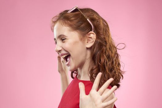 Cheerful little girl childhood dark glasses red dress lifestyle pink background. High quality photo