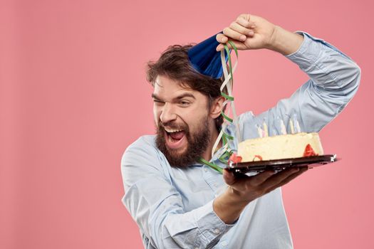 Bearded man with cake on pink background birthday party corporate emotions model loneliness. High quality photo