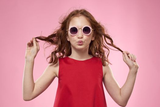 Cheerful little girl childhood dark glasses red dress lifestyle pink background. High quality photo