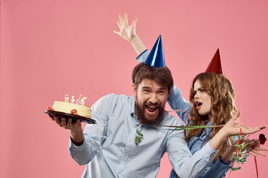 Party man and woman with cake on pink background corporate birthday. High quality photo