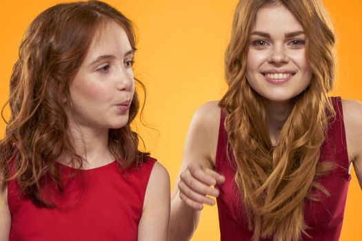 Mom and daughter in red dresses entertainment lifestyle yellow background. High quality photo