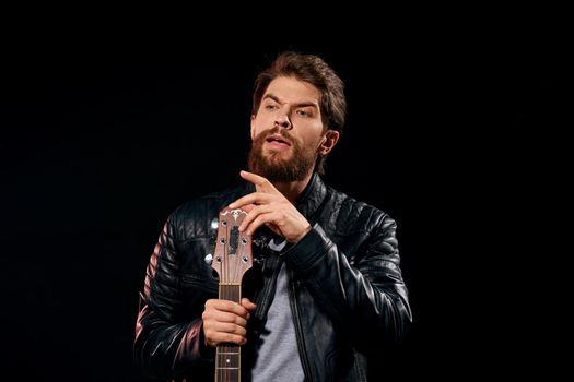 A man with a guitar in his hands leather jacket music performance rock star modern style dark background. High quality photo