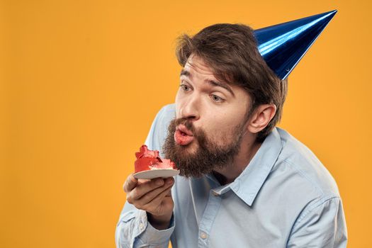 Man with cake on yellow background birthday party hat cropped view. High quality photo