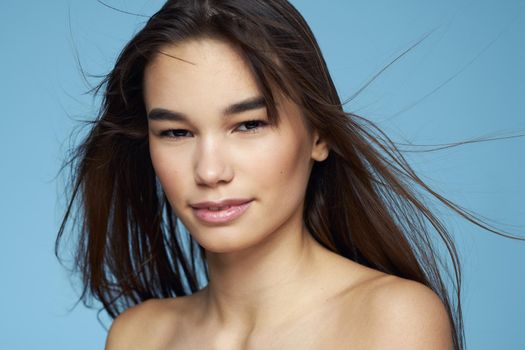 pretty brunette naked shoulders long hair skin care blue background. High quality photo