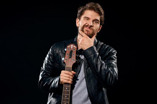 A man with a guitar in his hands leather jacket music performance rock star modern style dark background. High quality photo
