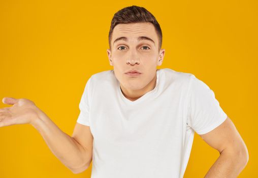Angry guy gesturing with his hands on a yellow background cropped view. High quality photo