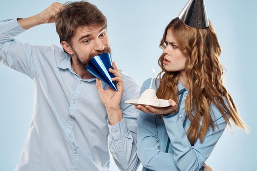 Cheerful man and woman with cake in a plate corporate party blue background. High quality photo