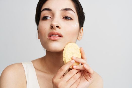 Pretty brunette clean face skin Sponge in hands with cosmetics. High quality photo