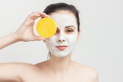 attractive brunette naked shoulders face mask hand sponge skin care. High quality photo
