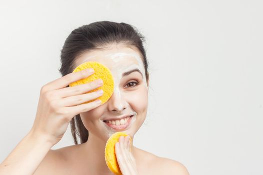 Cheerful brunette wipes face mask with sponges cropped view. High quality photo