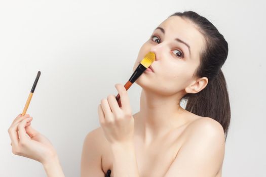 cheerful woman naked shoulders brushing cream on face. High quality photo