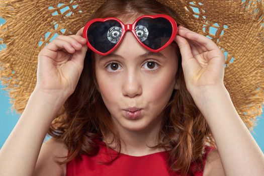 Girl in a beach Straw hat in sunglasses curly hair fun blue background. High quality photo