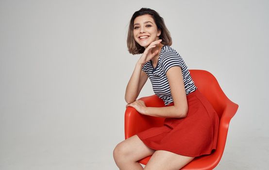 fashionable woman in a striped t-shirt sits on a red chair In a bright room Copy Space. High quality photo