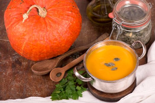 Bowl of pumpkin soup on rustic wooden background.