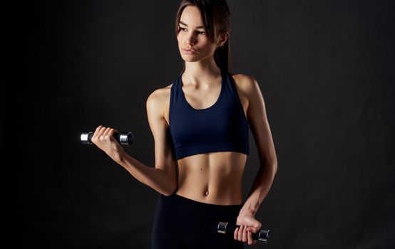 athlete with dumbbells in her hands on a black background arm muscles bodybuilder fitness. High quality photo