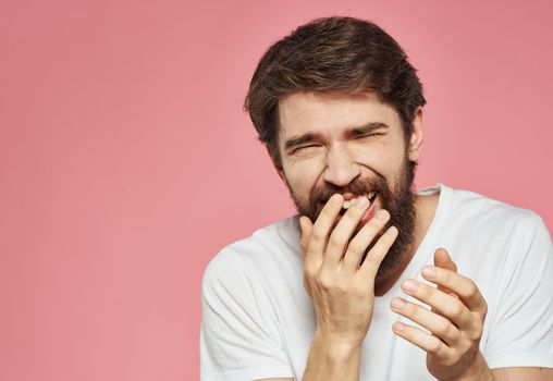Portrait of a guy in a white t-shirt on a pink background cropped view of fun emotions. High quality photo