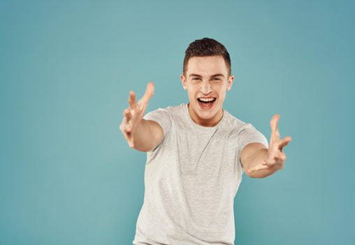 Cheerful man in T-shirt emotions gestures with hands blue background. High quality photo