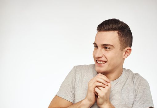 Cheerful man gesturing with his hands on a gray Studio T-shirt. High quality photo