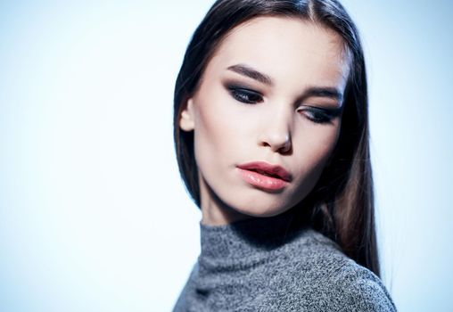 Portrait of a beautiful brunette in a gray sweater and eye shadow, evening makeup. High quality photo