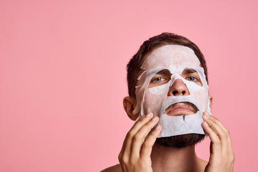 Man with bare shoulders clean skin face care pink background. High quality photo