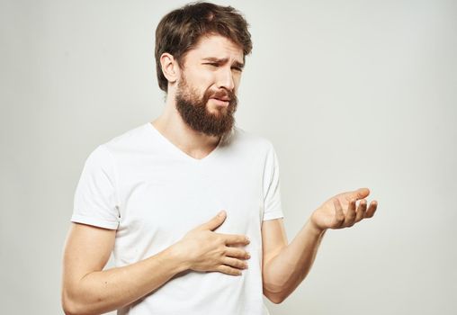 A man in a white T-shirt gestures with his hands on a light background cropped view of the emotion model. High quality photo