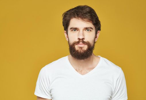 Brunette man on a yellow background in a white t-shirt cropped view. High quality photo