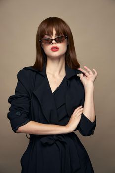 Stylish Woman Sunglasses beige background black coat studio