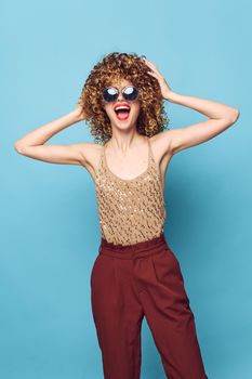 Sexy model Curly hair smile red lips attractive look blue background brown pants cropped view