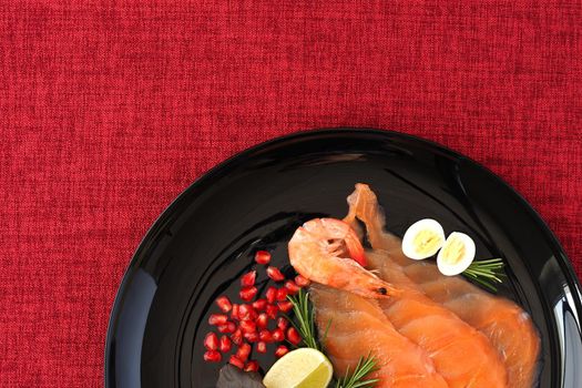 Red fish. A dish of seafood, salted salmon and shrimp on a black flat plate and a red background. Fled Lei. High quality photo