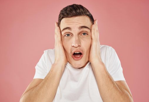 Happy man on pink background gesturing with hands in white t-shirt cropped view. High quality photo