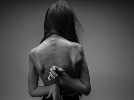 Nude woman in black and white photo gesturing with hands back view. High quality photo