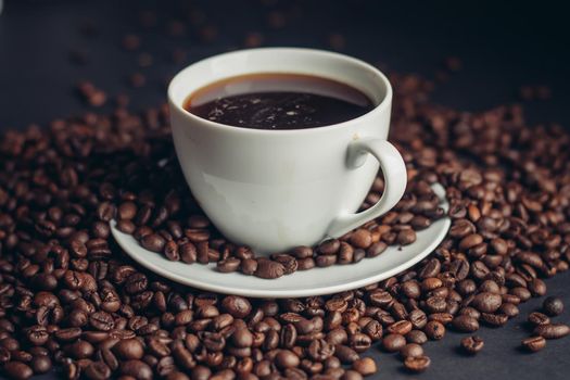 coffee beans sprinkled on a gray table and a cup saucer arabica drink. High quality photo