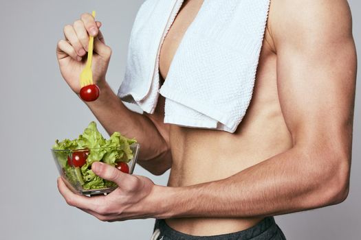 athletic man with a pumped-up torso towel on his shoulders a plate of salad healthy food. High quality photo