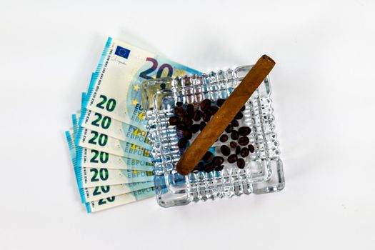 of 20 euro banknotes with ashtray and cigar on white background