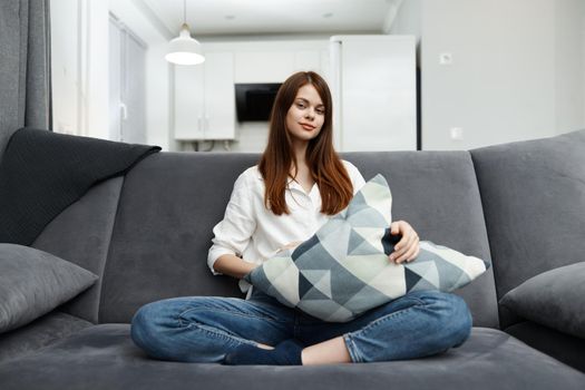 woman sitting on the couch in her free time with a pillow in her hands rest apartment interior. High quality photo
