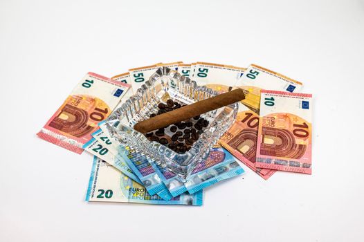50 20 10 euro banknotes with ashtray and cigar on white background